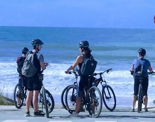 Groep fietsers bij zee kijkt naar golven